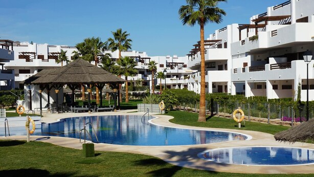 A resort with a swimming pool, a gazebo, and palm trees. - Casa Alexandra 4-person penthouse on the seafront in Mar de Pulpi. (Pulpí)