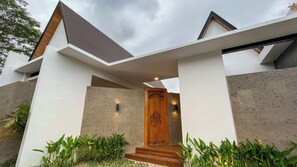 Une maison moderne avec une porte en bois, des murs en béton et un toit en pente.