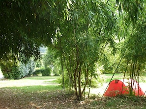 A red tent in a wooded area with dense foliage. - Camping L'Arrayade (Ger)