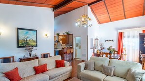 Amplia sala de estar con dos sofás, un comedor y una cocina al fondo.