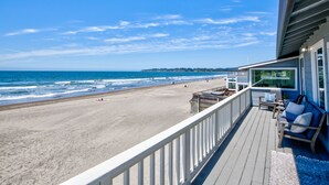 A beach view from a balcony with a railing, a deck, and a seating area with cushions. - Oceanfront Beauty with views from every room (Stinson Beach)
