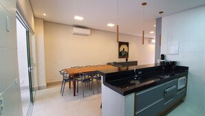 Eine moderne Küche mit schwarzem Arbeitsplatz, weißen Schränken und einem Essbereich mit Holztisch und -stühlen.