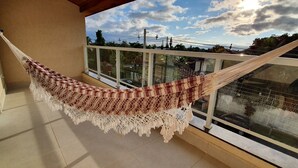 Eine Hängematte auf einem Balkon mit Blick auf den Himmel und Gebäude.