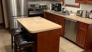 A kitchen with wooden cabinets, stainless steel appliances, a central island, and a built-in dishwasher.