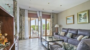 A spacious living room with a leather sofa, a glass coffee table, and a view through a glass door to an outdoor area. - Alcam Can Macia (Corbera De Llobregat)