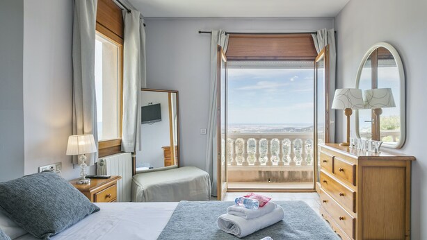 A hotel room with a bed, a dresser, a nightstand, a lamp, a mirror, and a balcony with a view. - Alcam Can Macia (Corbera De Llobregat)