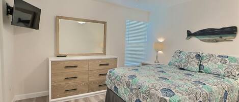 A bedroom with a bed, dresser, ceiling fan, TV, and a wall-mounted fish decoration.