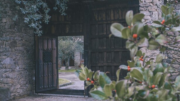 Un edificio de piedra con una puerta de madera grande y un camino que lleva a un patio.