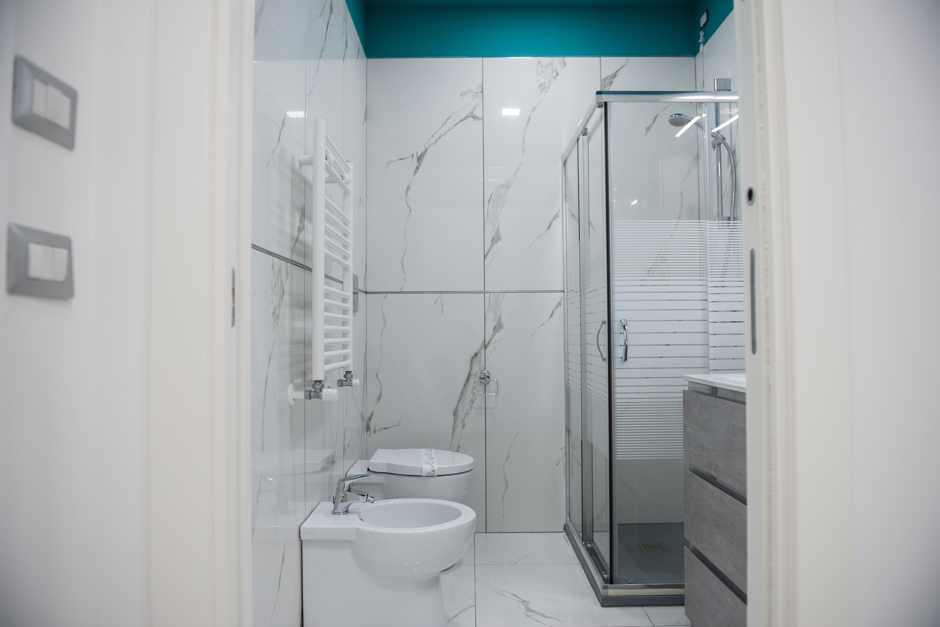 Un bany modern amb dutxa envoltat de vidre, un vàter blanc i un bidet.