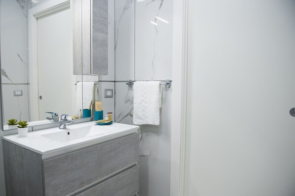 Un baño moderno con un lavamanos blanco, un espejo y un perchero para toallas.