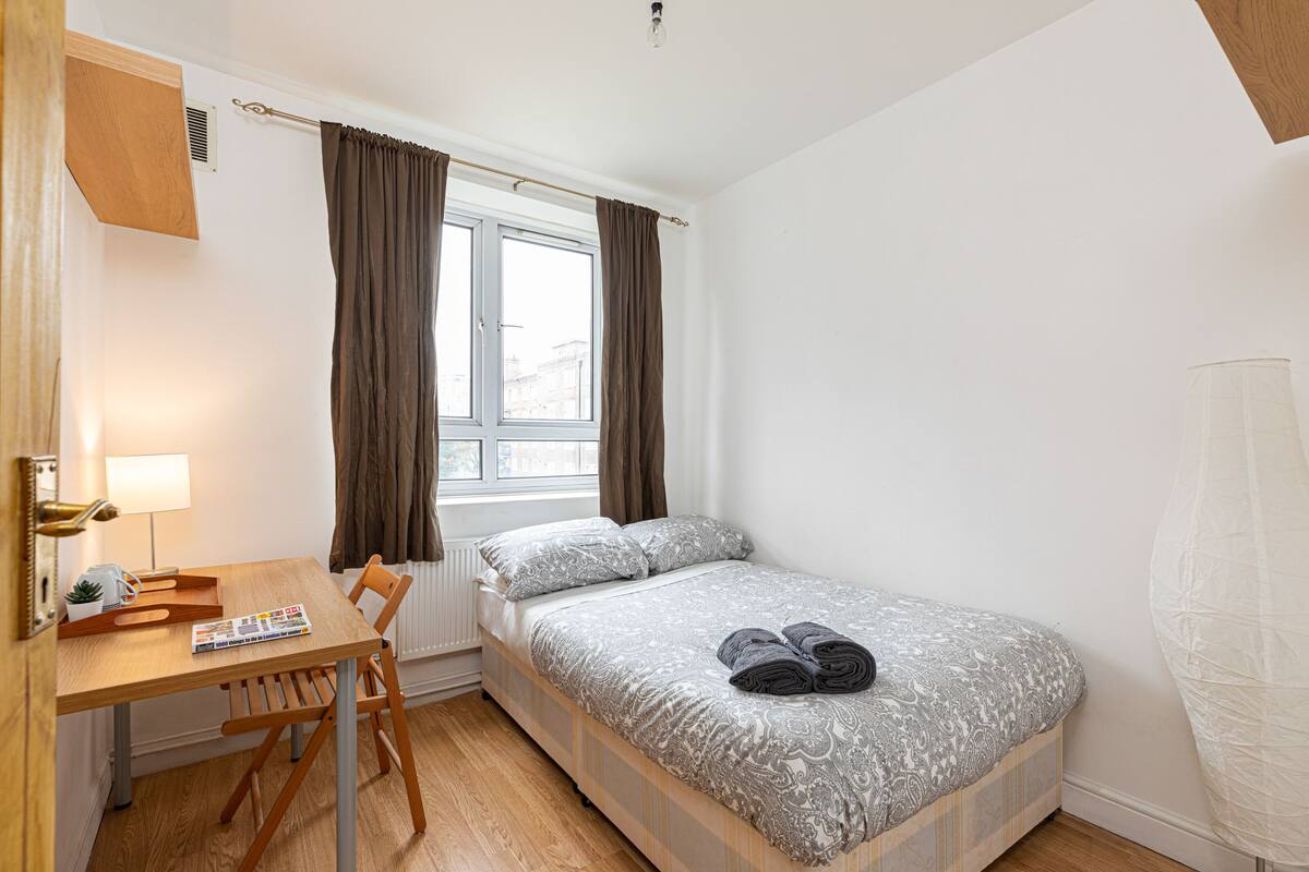 A small, tidy room with a bed, a table, and a chair.