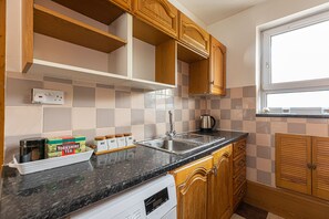 A kitchen with wooden cabinets, a granite countertop, a built-in dishwasher, and a window with a view. - Tower Bridge Accommodation - 1 (London)