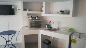 A compact kitchenette with a built-in oven, a sink, and a trash bin. - Classy Mykonian Studio - Ornos (Mykonos)