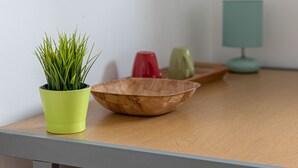 A wooden table with a green plant in a yellow pot, a wooden bowl, and a green lamp. - Tower Bridge Accommodation - 5 (London)