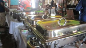 Disposição de buffet com vários rechauds de aço inoxidável sobre uma mesa.