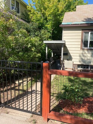 A residential area with a house, a covered porch, and a fenced yard.