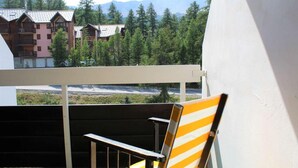 A balcony with a wooden chair and a view of a mountain landscape.