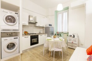 A compact kitchen with a washing machine, a microwave, and a refrigerator.