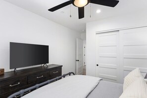 A bedroom with a bed, a television on a dresser, a ceiling fan, and a white door. - New Home 2 Mstrs, AC, EV Chgr, Pool Table, Lake Rights (Lake Arrowhead)