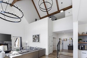 A spacious living area with a large sectional sofa, a fireplace, and a modern chandelier.