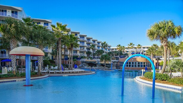 A resort pool area with multiple levels of buildings, palm trees, and lounge chairs. - Waterscape B210 COMPLETE REMODEL OCEAN & POOL VIEW! BEACH SERVICE! 2 KINGS BEDS! (Fort Walton Beach)