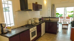 A compact kitchen with a gas stove, microwave, and dishwasher. There is a window providing natural light and a view of the outdoors. - Nice quiet house classified 3* in Narbonne with private overflowing pool (Narbonne)