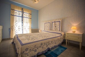 A bedroom with a bed, a nightstand, a lamp, and a blue rug.