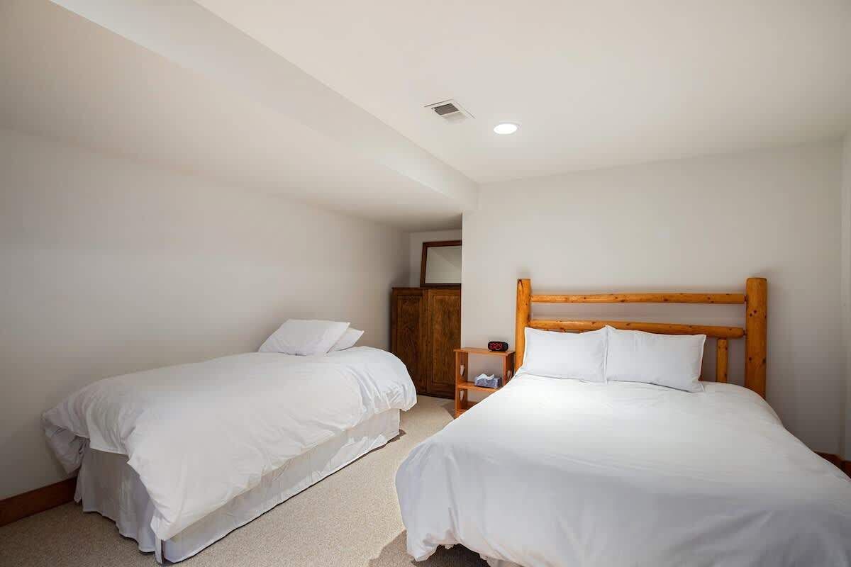 A bedroom with two single beds, a wooden headboard, a nightstand, and a wardrobe.