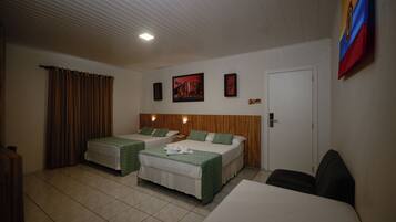 Habitación de hotel con dos camas, cabecero de madera, una puerta y una pared decorada con cuadros.