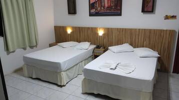 A hotel room with two beds, a wooden headboard, a painting on the wall, and a curtain.
