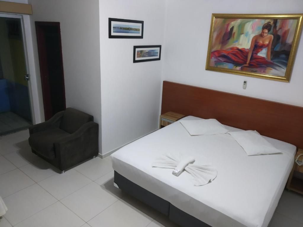 Une chambre d’hôtel avec un lit, une chaise et deux tableaux encadrés au mur.
