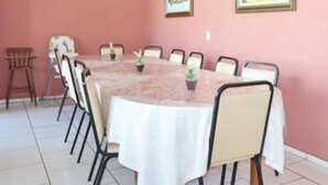 A dining area with a round table, chairs, and potted plants. - Hotel Iguacu (Dionisio Cerqueira)