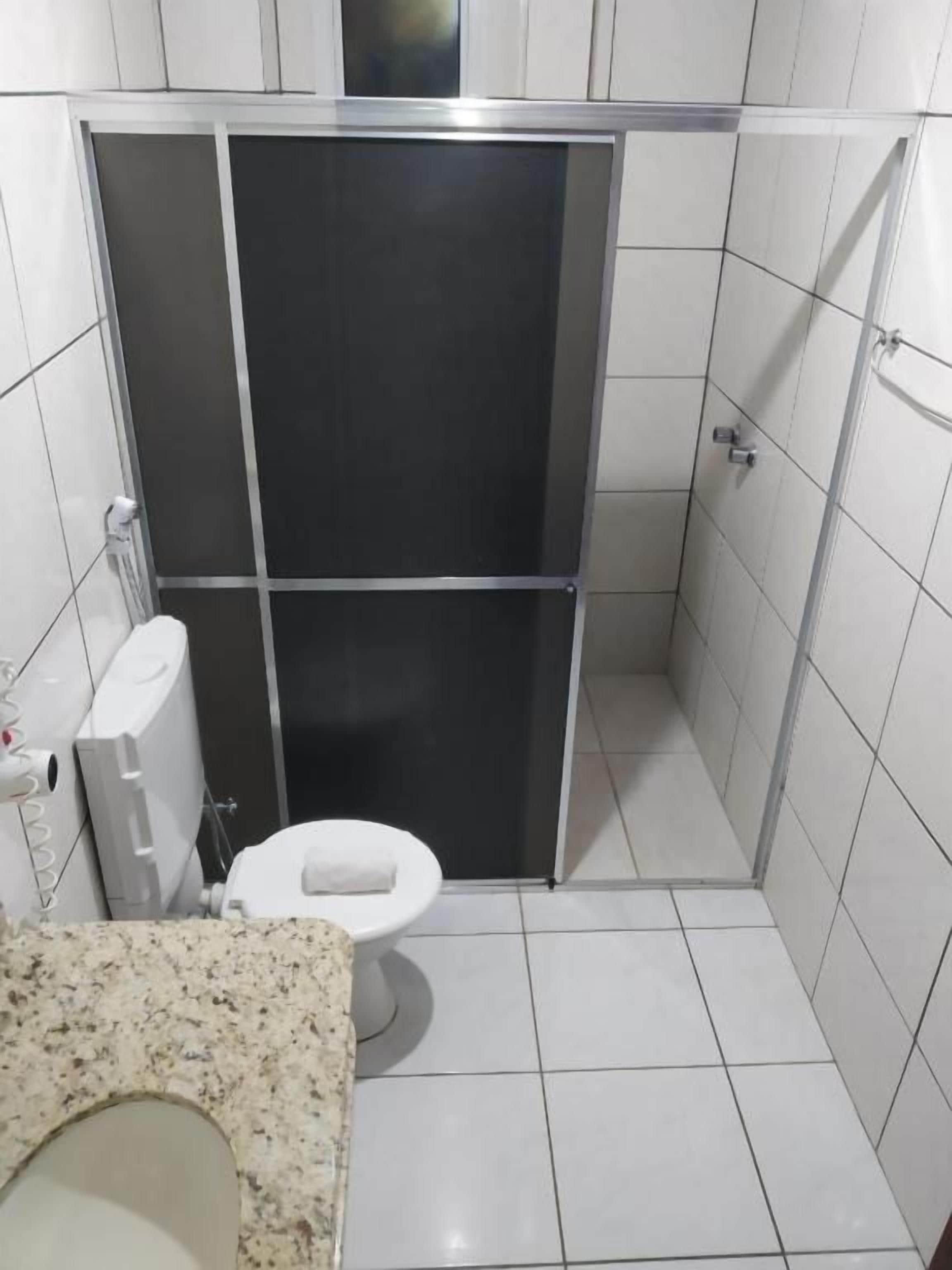 A bathroom with a toilet, a shower enclosure, and a sink.