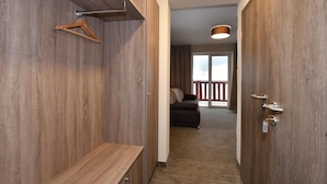 A hallway with wooden walls, a bench, a coat rack, and a door leading to a balcony with a view. - Hotel Studničky (Vernár)