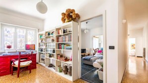 A spacious room with a red desk, a white bookshelf, and a comfortable seating area with a sofa and a coffee table. - La casa sul fiume (Ellera)