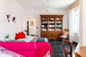 A living room with a sofa, a bookshelf, and a dining table. - La casa sul fiume (Ellera)
