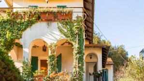 A traditional building with a stone staircase leading to a door with green shutters. - La casa sul fiume (Ellera)