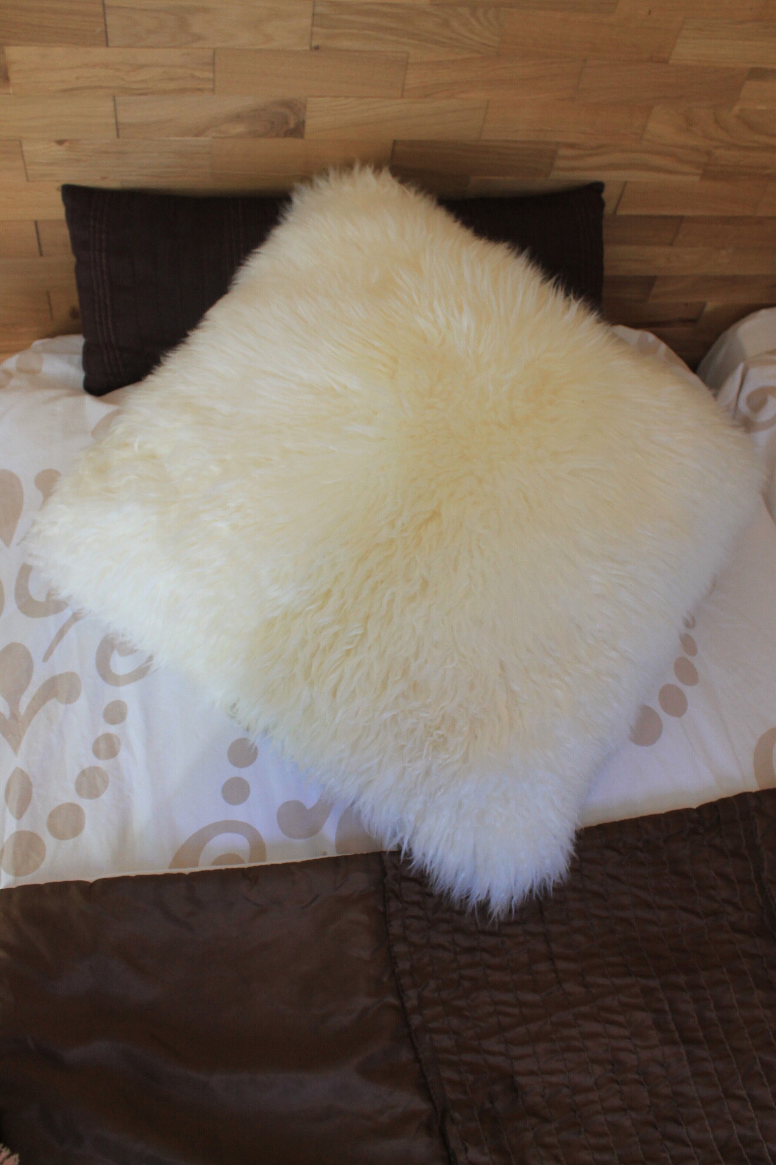 Un lit avec un oreiller blanc et moelleux et une couverture marron.