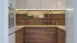 A compact kitchen with white cabinets, a wooden countertop, and a tiled backsplash. - Apartments Nadim (Skopje)