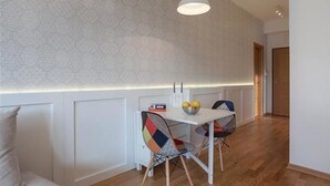 A modern dining area with a white table and chairs, a patterned wall, and a pendant light. - Apartments Nadim (Skopje)