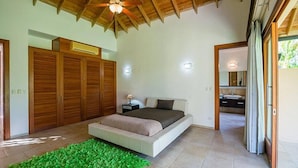 Quarto com cama grande, guarda-roupa de madeira e ventilador de teto.