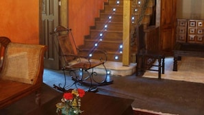 A lobby with a wooden staircase, a bench, a table with a vase of flowers, and a wall-mounted light fixture. - Posada Real El Señorío de la Serrezuela (Aldeanueva De La Serrezuela)