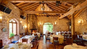 A rustic dining area with stone walls, wooden beams, and tables set for a meal. - Posada Real El Señorío de la Serrezuela (Aldeanueva De La Serrezuela)