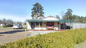 A small building with a covered porch, a red bench, and a car parked in front. - OYO Hotel Brookhaven MS Hwy 51 North (Brookhaven)