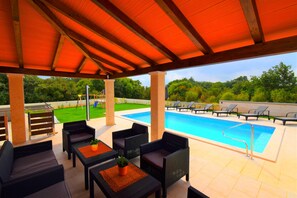 Un espace extérieur avec une piscine, des chaises longues et un coin salon abrité.