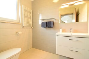 Ein Badezimmer mit Toilette, Waschbecken, Spiegel und Handtuchhalter.