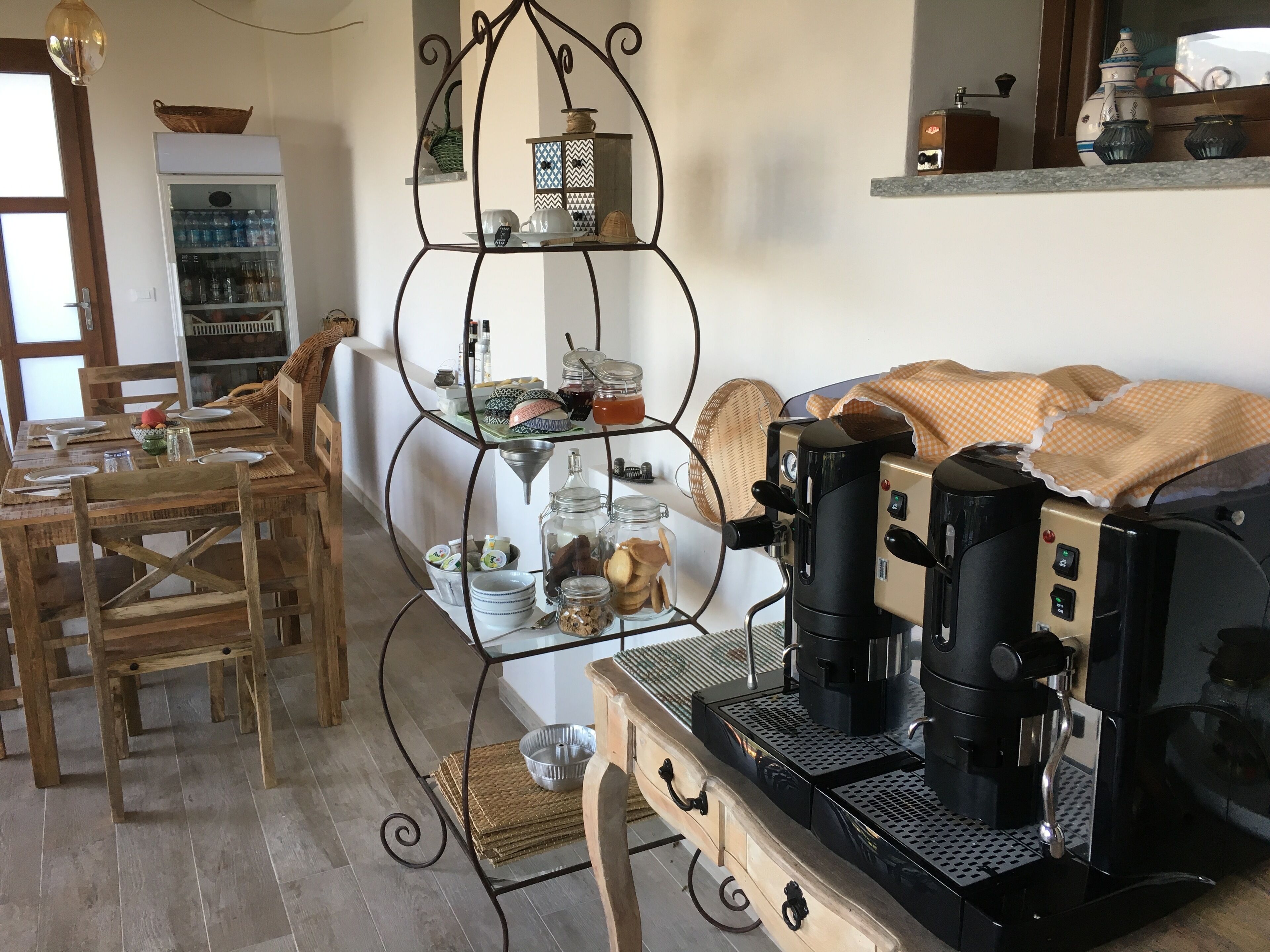 A cozy dining area with wooden furniture, a coffee machine, and a decorative shelf with various items.