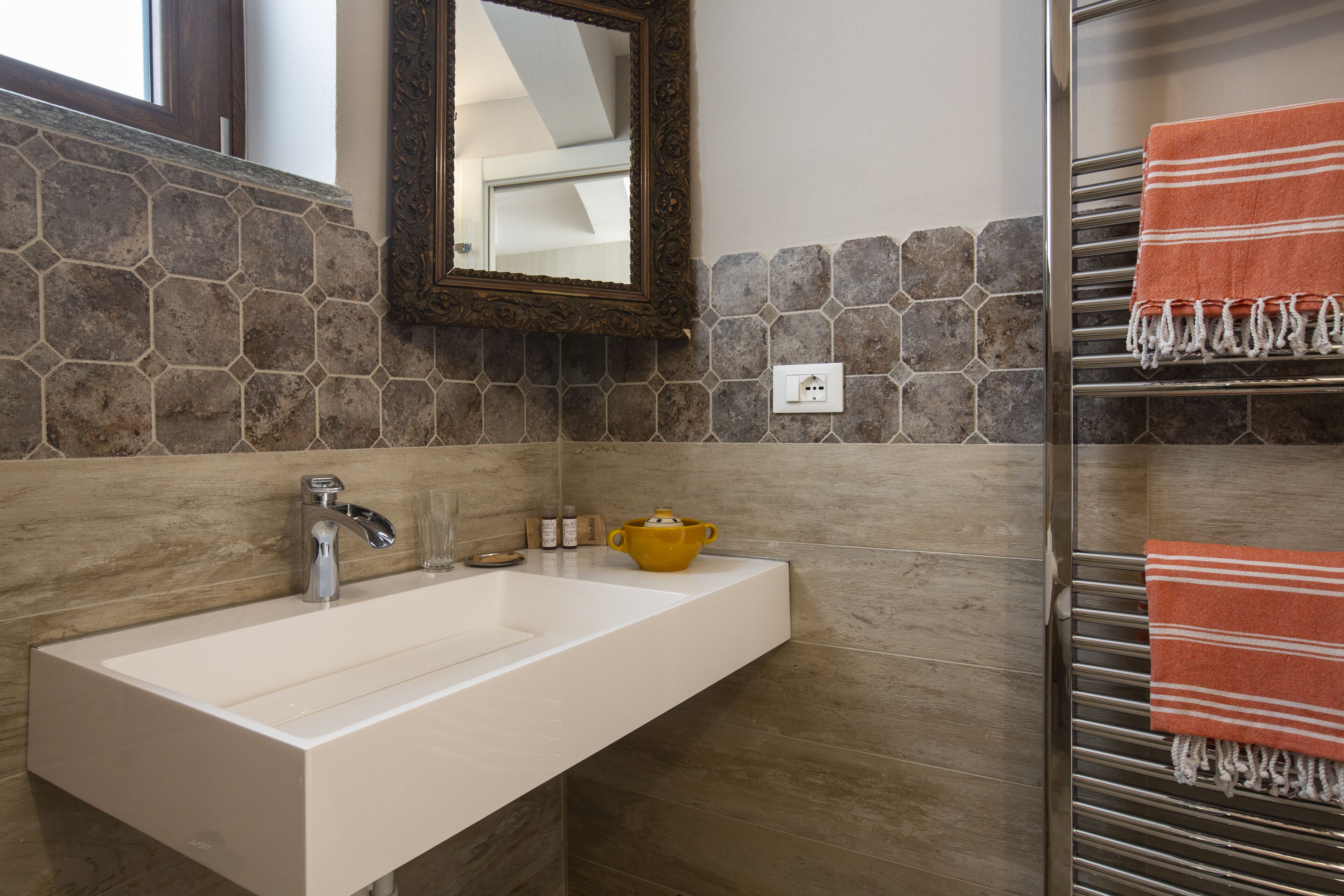 Une salle de bain avec un lavabo blanc, un miroir et un porte-serviettes avec des serviettes.