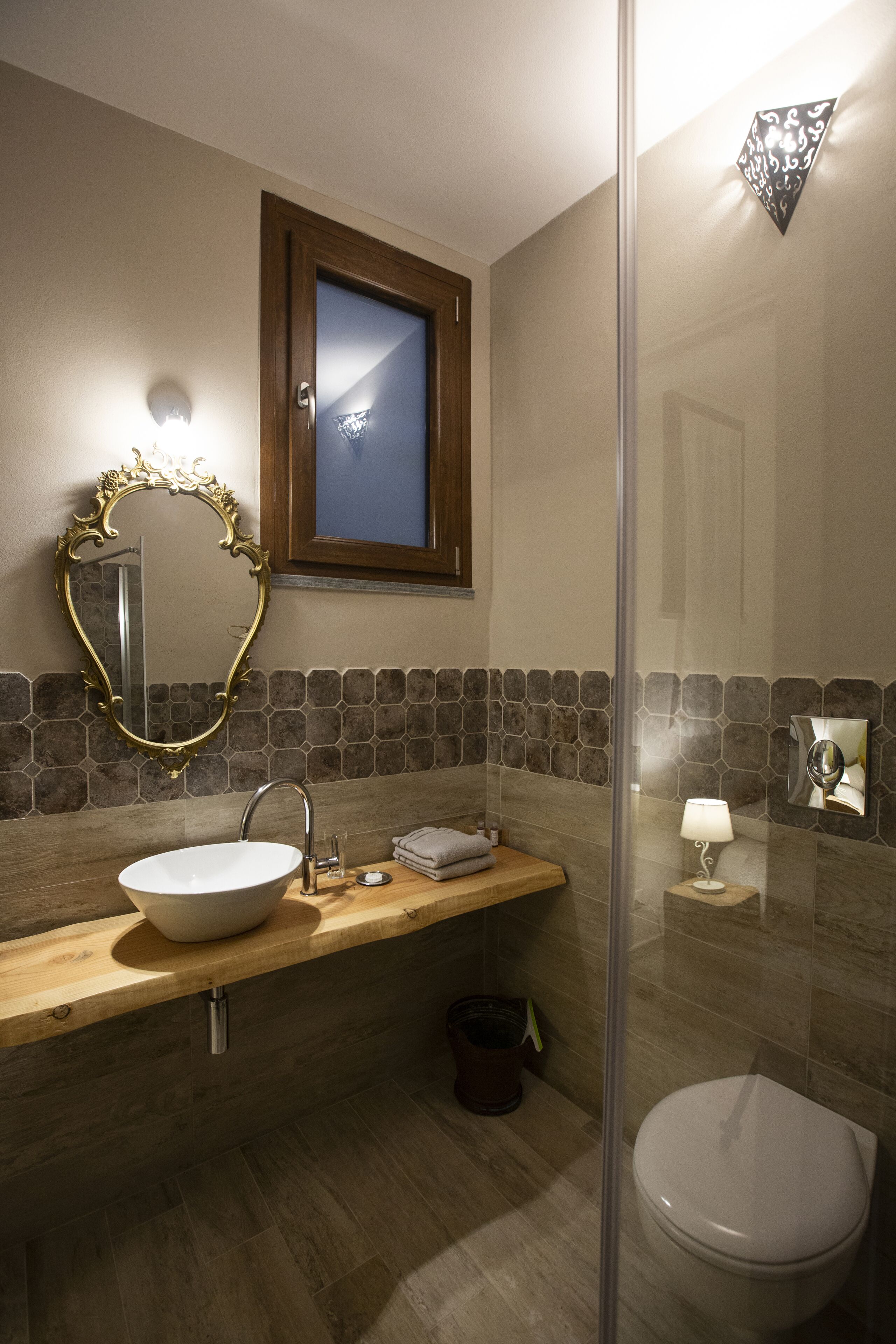 Une salle de bain avec un meuble-lavabo en bois, un lavabo blanc, un miroir, une serviette et une cabine de douche en verre.