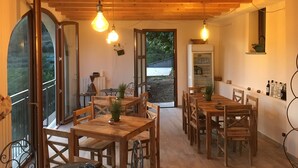A dining area with wooden tables and chairs, a view through large windows, and hanging light fixtures. - Agriturismo LaValleggia (Tovo San Giacomo)